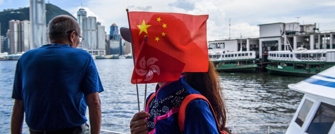 Dam med kinesisk flagga framför ansiktet i Hongkong